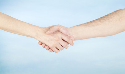 Hand shake between a man and a woman on sky background