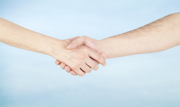 Hand shake between a man and a woman on sky background