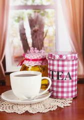 Jar and cup of tea on table in room