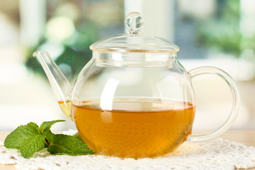 Teapot with mint on table in room
