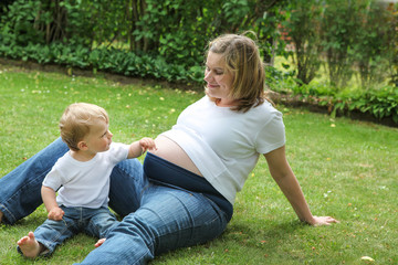 Fototapeta premium Pregnant woman and little son in summer garden