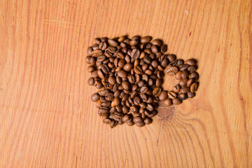 form a coffee cup made of coffee beans on the wood background