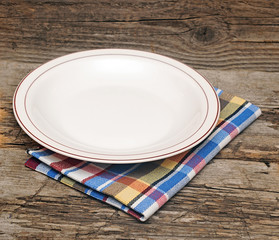Empty plate on tablecloth on wooden table