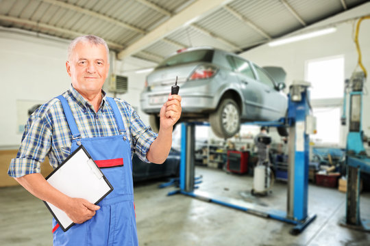 Mechanic holding a car key atauto repair shop during an automobi