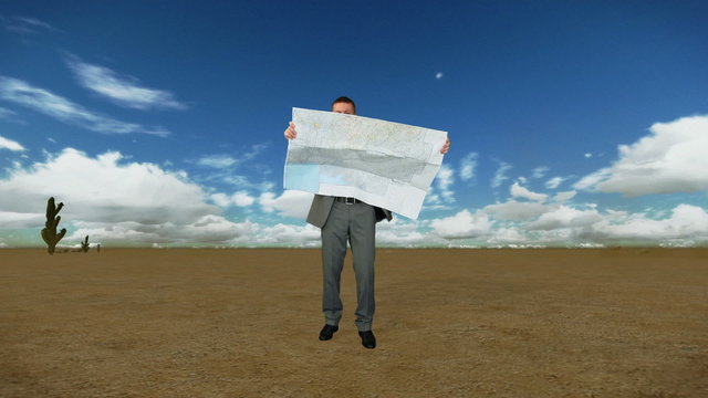 Businessman with Map in Desert with Time Lapse Clouds
