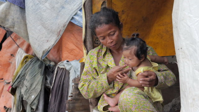Mother feeding baby in cambodian slums, close to dump area