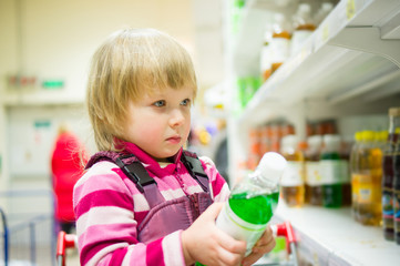 Adorable girl select bottle of soda drink stay in shopping cart