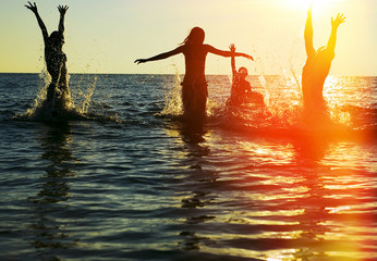 Silhouettes of people jumping in ocean - 49335596