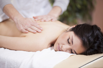 Fototapeta na wymiar Cute young woman getting a back massage at a spa
