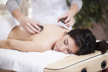 Very relaxed young woman getting a stone massage at a spa