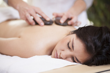 Obraz na płótnie Canvas Pretty woman getting a hot stone massage at home