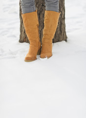 Closeup on female legs in winter boots on snow