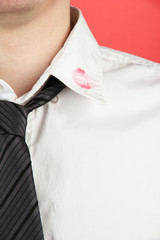 Lipstick kiss on shirt collar of man, on red background