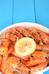 Shrimps with lemon on plate on wooden table close-up