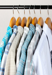 Shirts with ties on wooden hangers on light background