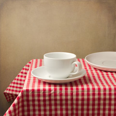 Table setting with white coffee cup over gunge background