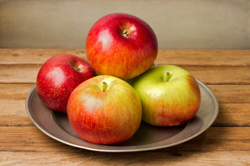 Naklejka na ściany i meble Fresh red apples on plate on wooden table