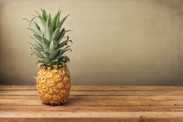 Pineapple on wooden table over crunge background