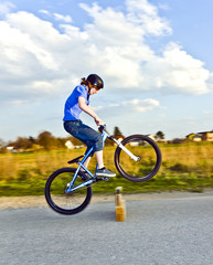 young boy jumping with his dirk bike over a barrier at the stree
