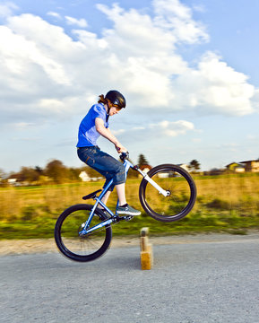 Young Boy Jumping With His Dirk Bike Over A Barrier At The Stree