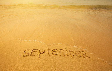 September - written in sand on beach texture