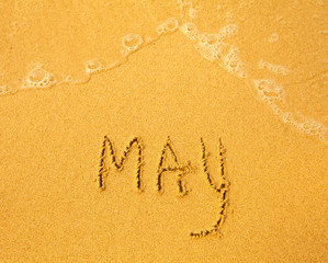 May - written in sand on beach texture
