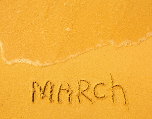March - written in sand on beach texture