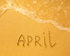 April - written in sand on beach texture