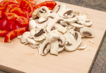 Chopped mushrooms and red peppers on wooden chopping board