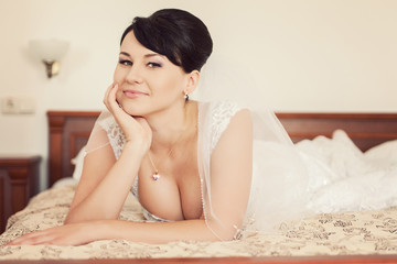 Obraz na płótnie Canvas Portrait of happy beautiful bride lying on bed in wedding day