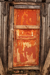 Old wooden orange door with a rusty lock