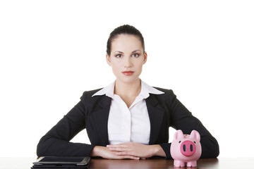 Businesswoman at the desk with tablet and piggy bank