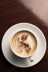 A cup of coffee on a wooden table top view