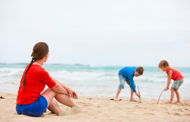 Fototapeta na wymiar Mother and two kids at tropical beach