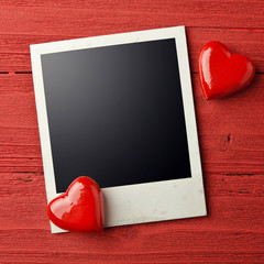 Blank photo and small red hearts on grunge background.