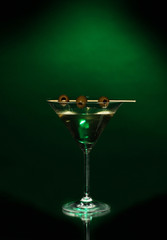 Martini glass and olives on dark background