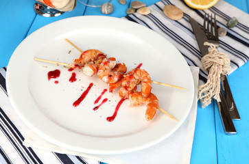 Grilled shrimp with sauce on plate on wooden table close-up