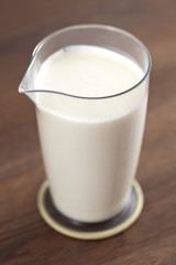 The volumetric glass with milk costs on a table.
