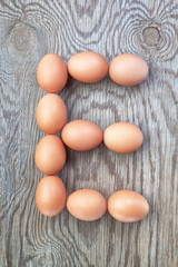 A letter e from the eggs for easter. On a wooden texture.