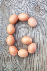 A letter g from the eggs for easter. On a wooden texture.