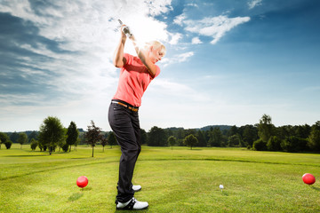 Young golf player on course doing golf swing