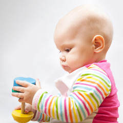 Little baby plays with wooden toy, closeup portrait