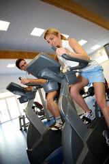 Fototapeta na wymiar People exercising on bicycles in fitness gym