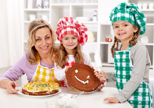 Little Chef Girls With Their Mother Making A Cake