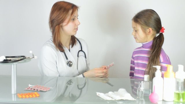 Pediatrician woman gives a little girl pill