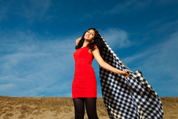 Indian girl with long hair dressed in red on the beach in summer