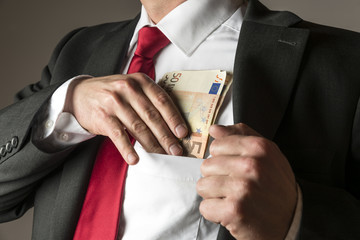 Businessman putting money in pocket - obrazy, fototapety, plakaty
