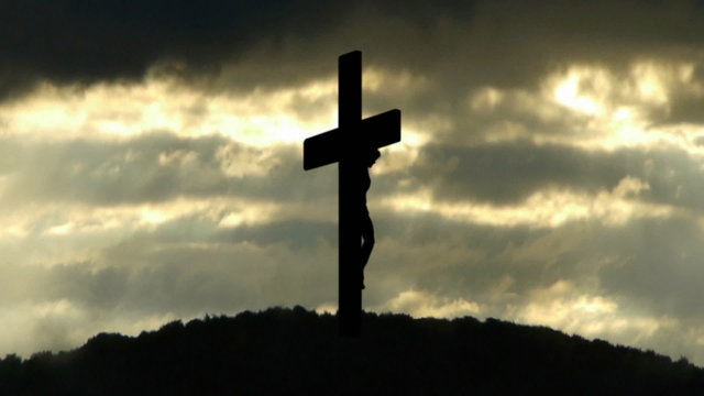 Silhouette of Holy Cross on background of storm clouds.