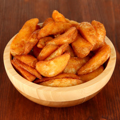 Appetizing village potatoes in bowl on wooden table close-up
