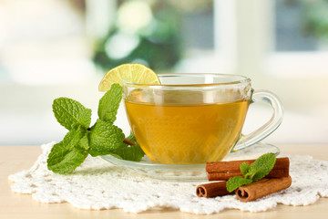 Cup of tea with mint and cinnamon on table in room